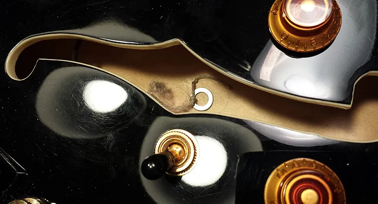 Petites pièces d’une guitare alignées sur l’établi